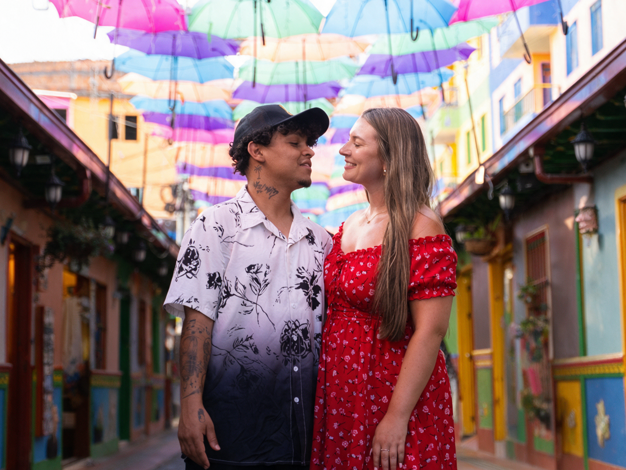 Pareja bajo las sombrillas de colores de una calle de Guatapé