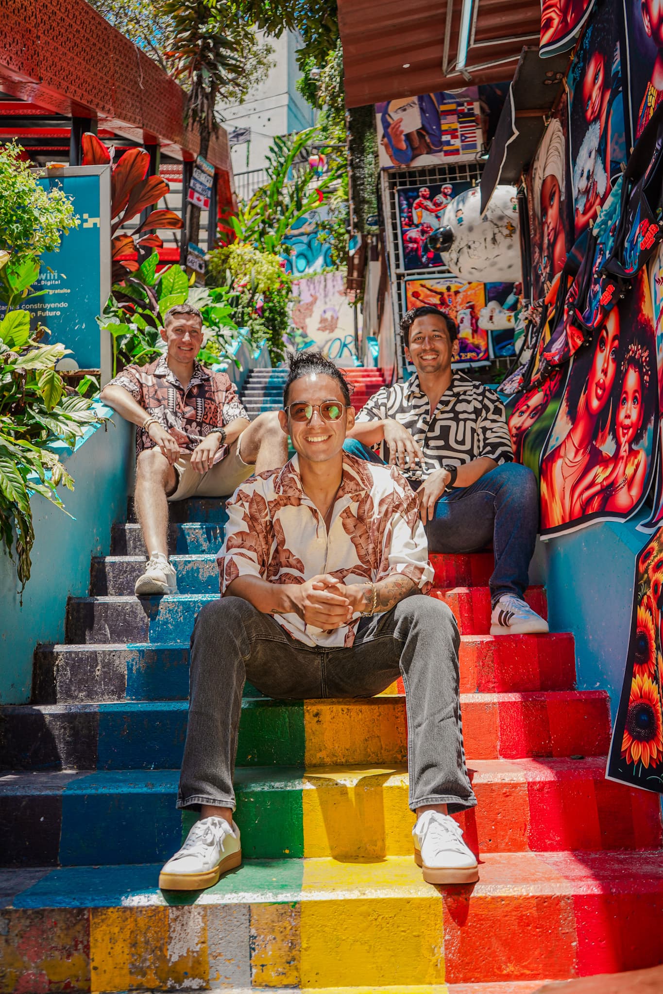 Three travelers sitting on brightly painted steps, among murals in Comuna 13
