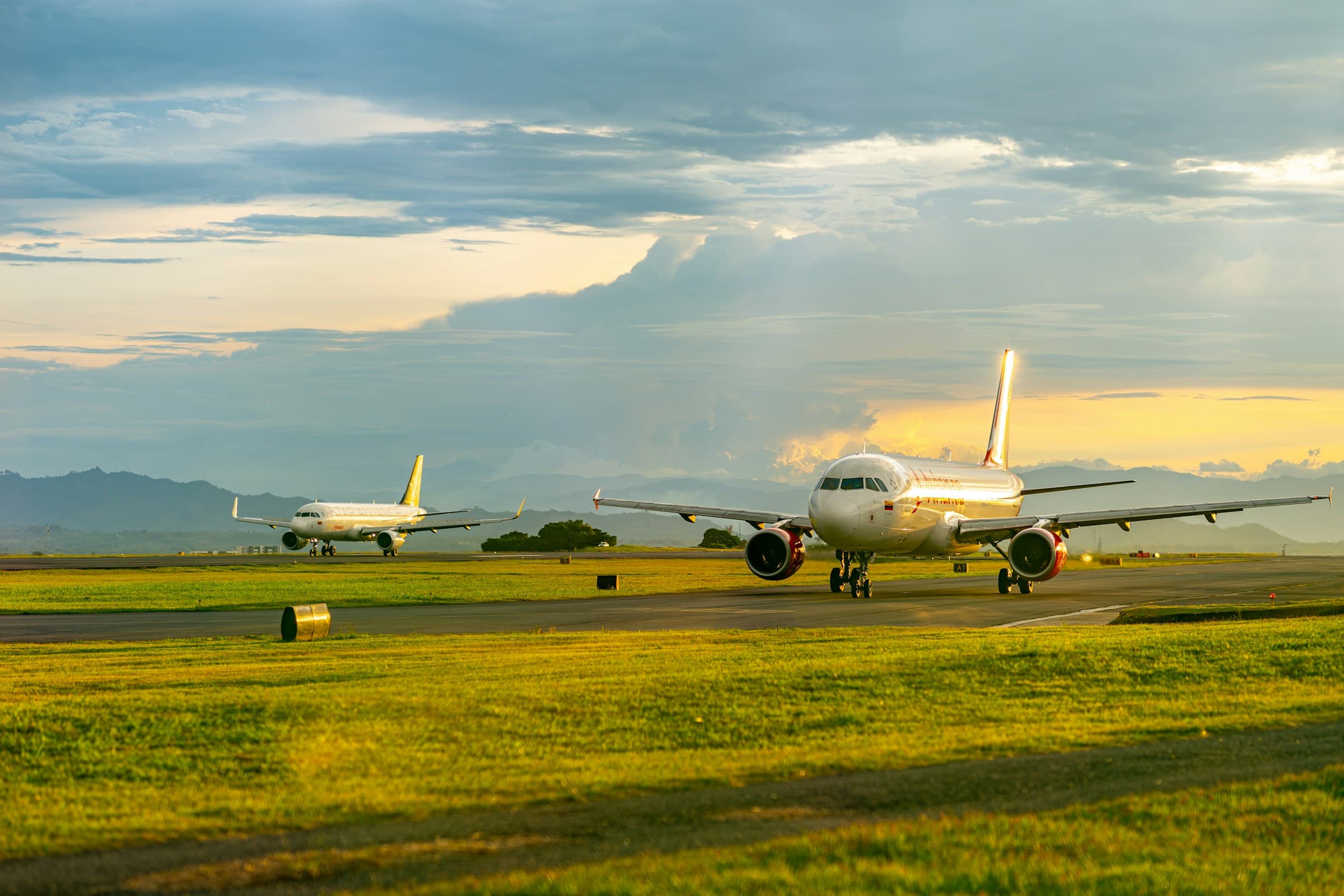 Two planes on the runway of a Colombian airport at sunset