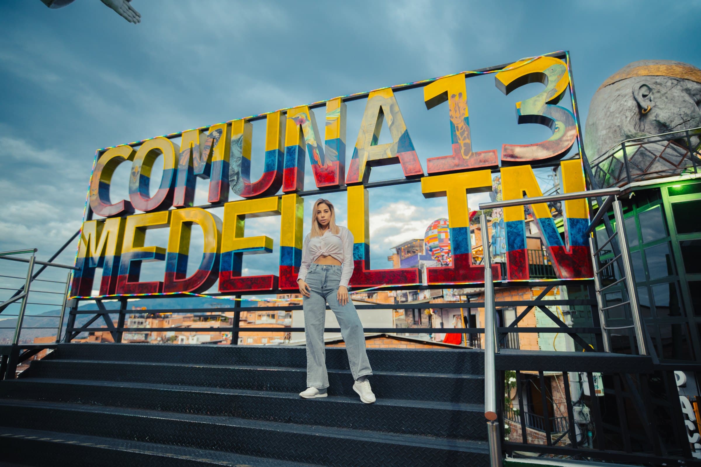 Traveler on the steps in front of the colorful "Comuna 13 Medellín" sign