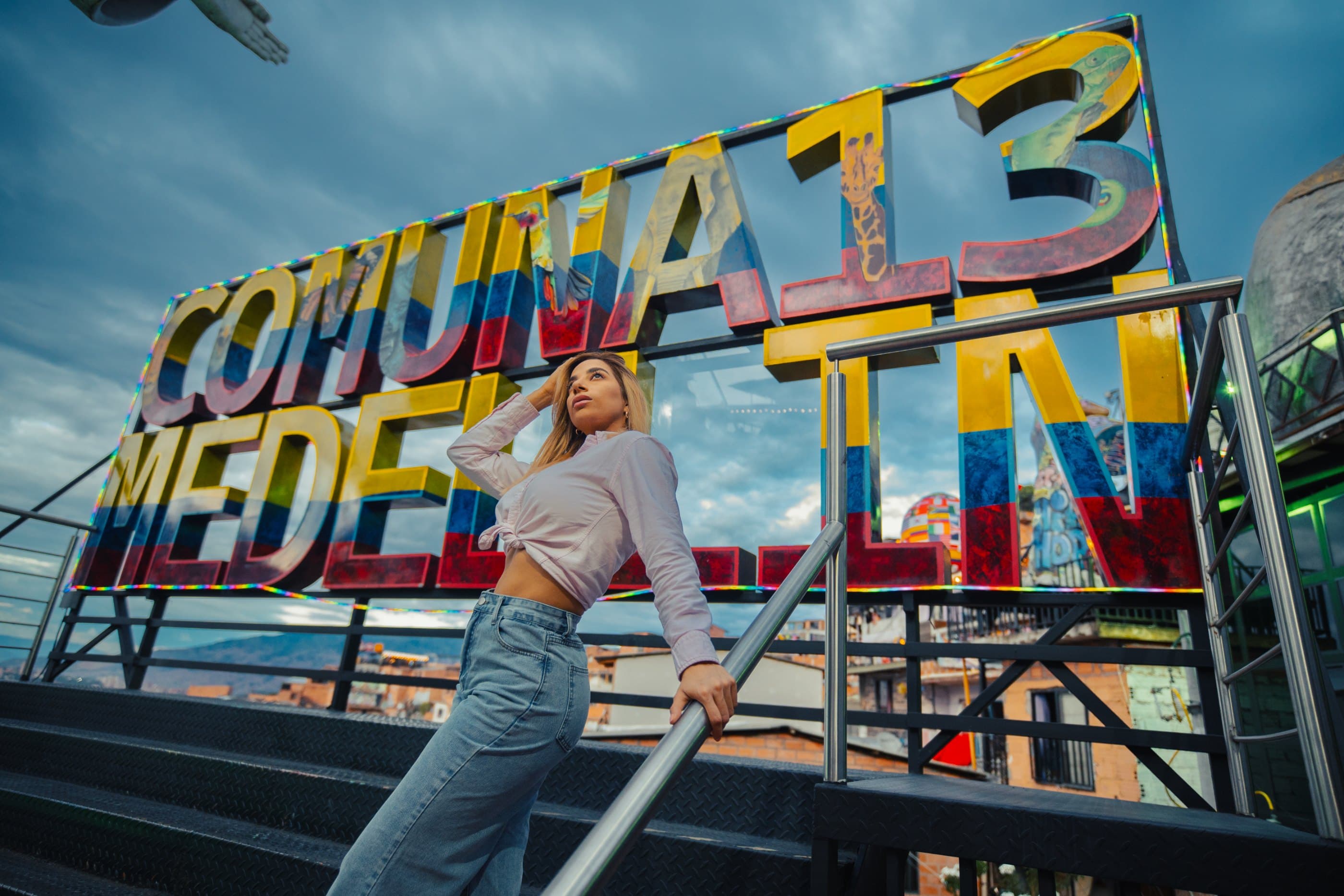 Traveler under the Comuna 13 Medellín sign, next to the escalators